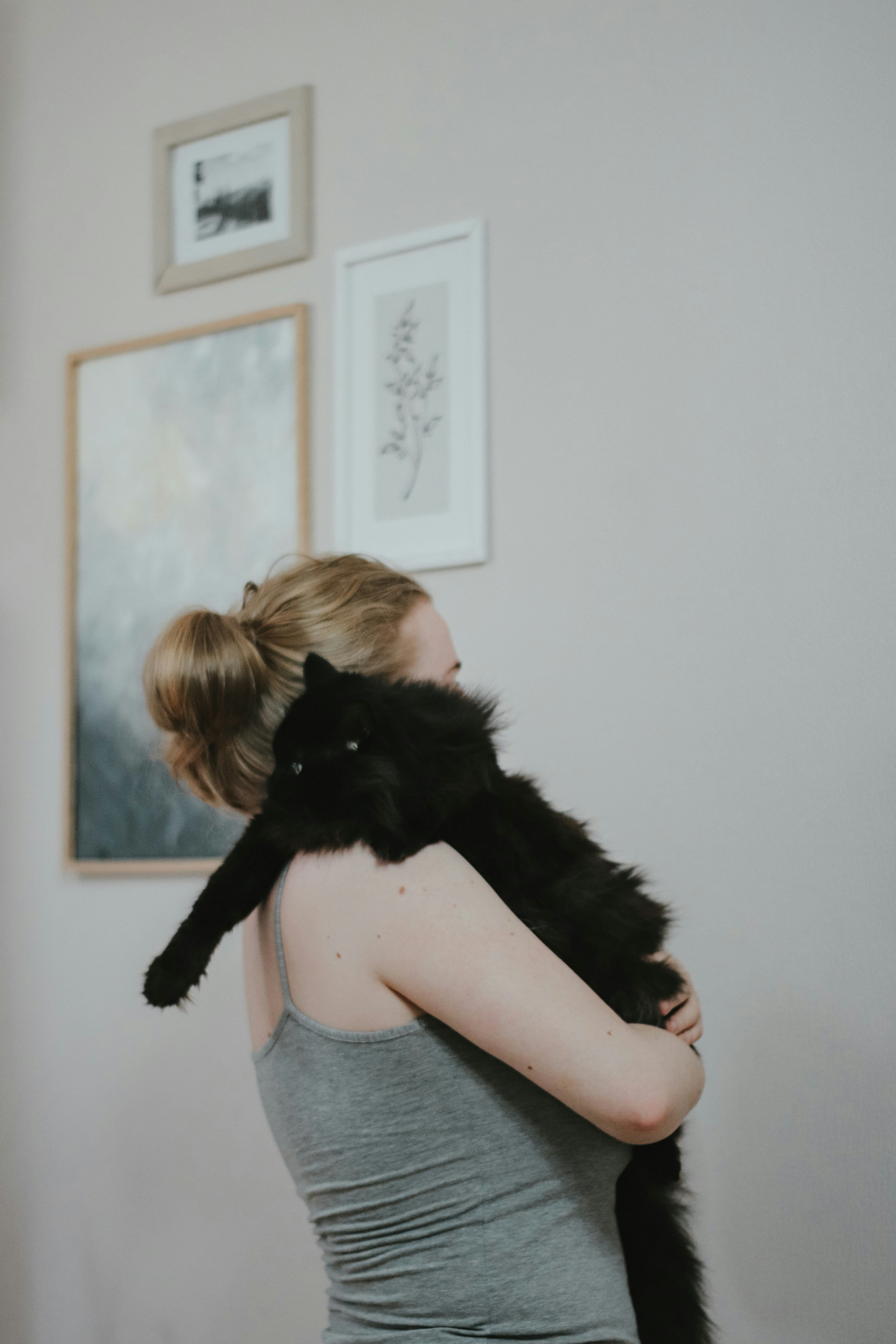 A woman holding a long haired black cat