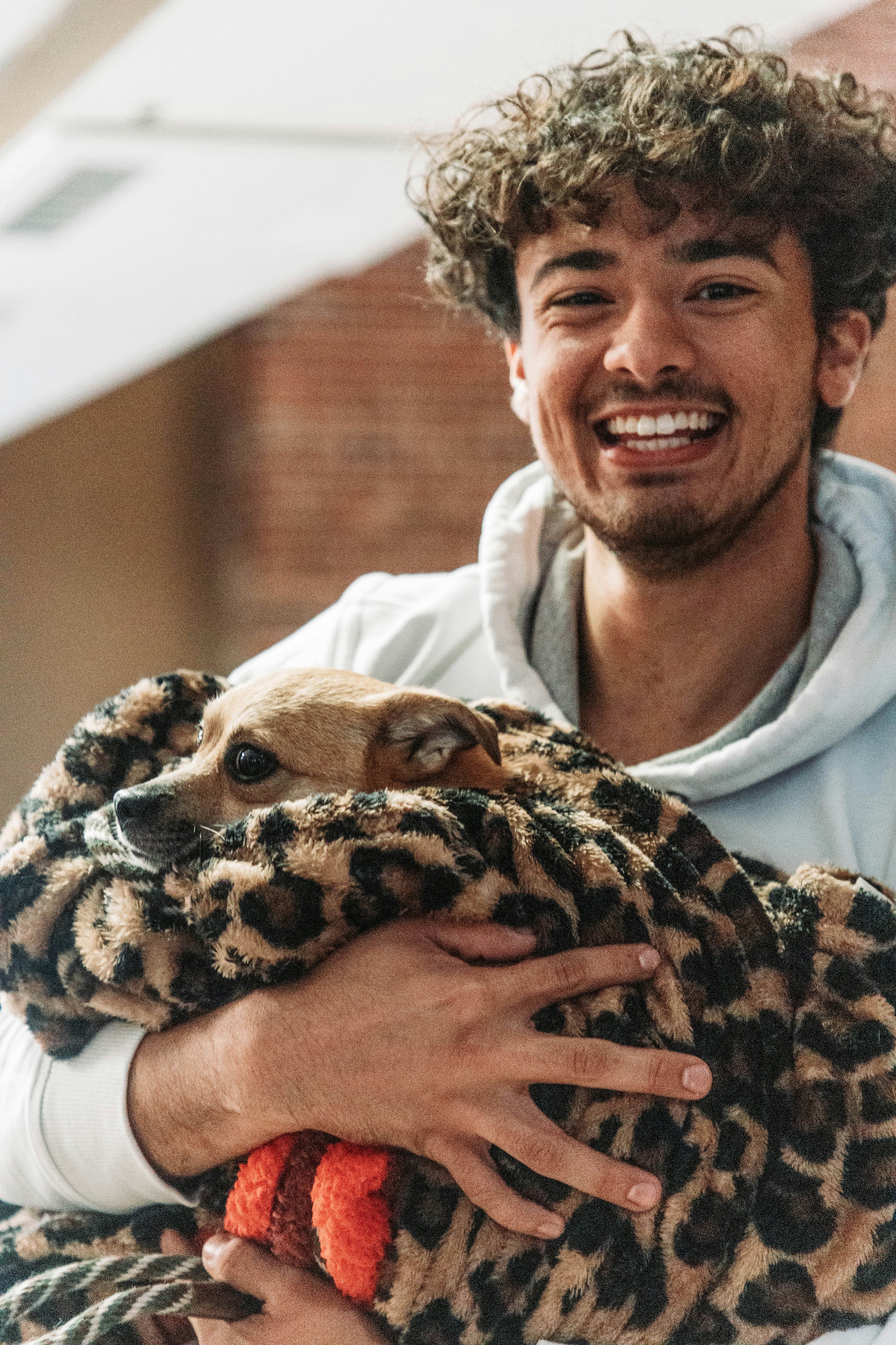 A man holding in a blanket a small brown dog